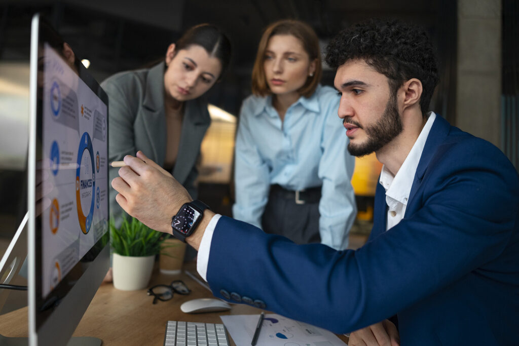 Profissionais discutindo e analisando gráficos de resultados de marketing digital em um escritório, focando em métricas de performance.